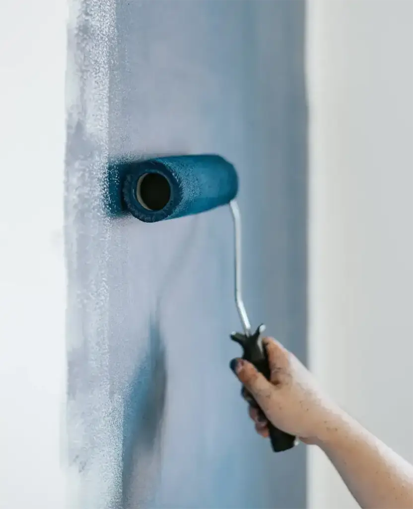 Rodillo de pintura pintando una pared de azul
